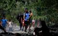 Grupos de personas migrantes caminan en la selva del Darién, para luego ser trasladados en canoa desde la Quebrada León hasta a la comunidad de Bajo Chiquito (Panamá). EFE/ Bienvenido Velasco