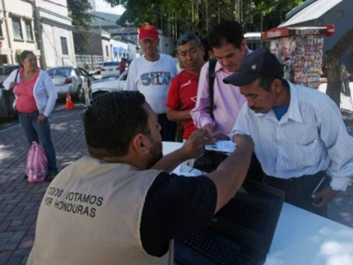 A worker of the Honduran Electoral Supreme Court (TSE) provides information helping citizens to find their polling place, ahead of Sunday's national elections, in Tegucigalpa on November 25, 2017.Honduras is going into elections on Sunday that, if voter surveys are right, will see current President Juan Orlando Hernandez given a new four-year mandate -- despite a one-term limit in the constitution. His conservative National Party contends that a 2015 Supreme Court ruling voided that restriction. But the opposition disputes that, saying the court does not have the power to overrule the constitution. / AFP PHOTO / RODRIGO ARANGUA