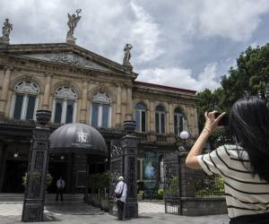 <i>Un turista toma una fotografía frente al Teatro Nacional de San José, el 18 de julio de 2024. El número de turistas que visitan Costa Rica aumentó un 14,5% en el primer semestre de este año, en comparación con el mismo período de 2023. FOTO Ezequiel BECERRA/AFP</i>