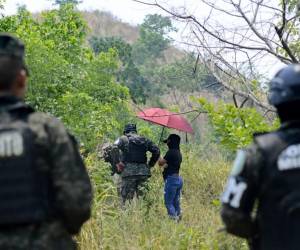 <i>Miembros de las Fuerzas Armadas de Honduras hacen guardia mientras las autoridades y el Centro de Medicina Legal y Ciencias Forenses buscan los restos de al menos 40 vecinos presuntamente ejecutados por la banda criminal Los Aguacates, en Lomas del Carmen, en San Pedro Sula, 180 kilómetros al norte de Tegucigalpa. , el 27 de mayo de 2024. FOTO AFP</i>