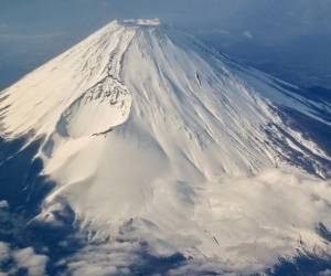 <i>Esta foto tomada el 30 de enero de 2024 muestra una vista aérea del Monte Fuji, la montaña más alta de Japón con 3.776 metros (12.389 pies), desde la ventana de un avión de pasajeros. El 13 de mayo de 2024, las autoridades japonesas anunciaron un sistema de reserva en línea para el sendero más popular del Monte Fuji que intentaba combatir el exceso de turismo en el volcán activo.Richard A. Brooks/AFP</i>