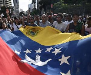 <i>Manifestantes ondean una gran bandera venezolana durante una protesta contra el gobierno del presidente venezolano Nicolás Maduro en Caracas el 29 de julio de 2024, un día después de las elecciones presidenciales venezolanas. FOTO Raul ARBOLEDA / AFP</i>