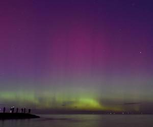 <i>La gente observa la aurora austral o luces del sur provocadas por una tormenta solar en la bahía de Port Phillip en Melbourne el 11 de mayo de 2024. FOTO Paul CROCK / AFP</i>