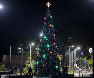 <i>Personas caminan junto a un árbol navideño este lunes, en Caracas (Venezuela). En un mensaje televisado, el presidente de Venezuela, Nicolás Maduro, anunció el adelanto de las fiestas navideñas: “Y por eso este año, en homenaje a ustedes, en agradecimiento a ustedes, voy a decretar el adelanto de la Navidad para el 1 de octubre. Arranca la Navidad el 1 de octubre para todos y todas. Llegó la Navidad con paz, felicidad y seguridad” . EFE/ Miguel Gutiérrez</i>