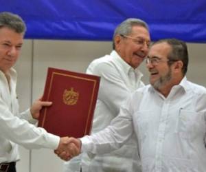 El presidente de Colombia, Juan Manuel Santos, estrecha la mano del líder guerrillero de las FARC Timoleón Jiménez 'Timochenko', tras firmar el acuerdo. Detrás, el presidente cubano Raúl Castro.