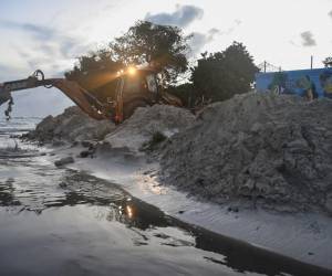 <i>Personal del Ministerio de Transporte, Obras e Infraestructura limpia arena del desagüe después del paso del huracán Beryl en los jardines de Oistins, Christ Church, Barbados, el 1 de julio de 2024. FOTO Randy Brooks/AFP</i>