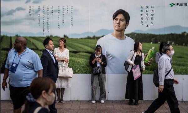 <i>La gente pasa junto a un anuncio con la foto de la estrella de béisbol de las Grandes Ligas (MLB), Shohei Ohtani, en Tokio, el 4 de junio de 2024. FOTO Yuichi YAMAZAKI / AFP</i>