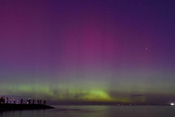 <i>La gente observa la aurora austral o luces del sur provocadas por una tormenta solar en la bahía de Port Phillip en Melbourne el 11 de mayo de 2024. FOTO Paul CROCK / AFP</i>