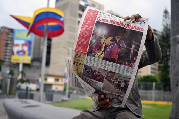 <i>Un hombre lee un periódico en Caracas el 29 de julio de 2024, un día después de las elecciones presidenciales venezolanas. El presidente Nicolás Maduro fue declarado ganador de las elecciones presidenciales de Venezuela, pero la oposición y los principales vecinos regionales rechazaron de inmediato los resultados oficiales. FOTO Raúl ARBOLEDA / AFP</i>