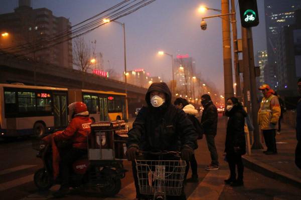 <i>En la imagen de archivo, peatones utilizan mascarillas para protegerse de la contaminación en Pekín (China). EFE/How Hwee Young</i>