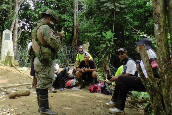 <i>El Servicio Nacional de Fronteras de Panamá (Senafront) habla con migrantes de diferentes nacionalidades que intentan cruzar la punta Asti, en la selvática provincia de Darién, municipio de Acandí, frontera entre Colombia y Panamá el 16 de julio de 2024. FOTO Yeison ROJAS/AFP</i>