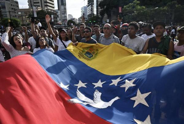 <i>Manifestantes ondean una gran bandera venezolana durante una protesta contra el gobierno del presidente venezolano Nicolás Maduro en Caracas el 29 de julio de 2024, un día después de las elecciones presidenciales venezolanas. FOTO Raul ARBOLEDA / AFP</i>