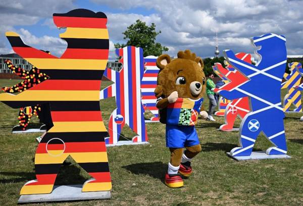 <i>La mascota 'Albaert' del próximo Campeonato Europeo de Fútbol UEFA Euro 2024 posa entre figuras en forma de oso con los colores de las naciones participantes en Berlín el 13 de junio de 2024.RALF HIRSCHBERGER/AFP</i>