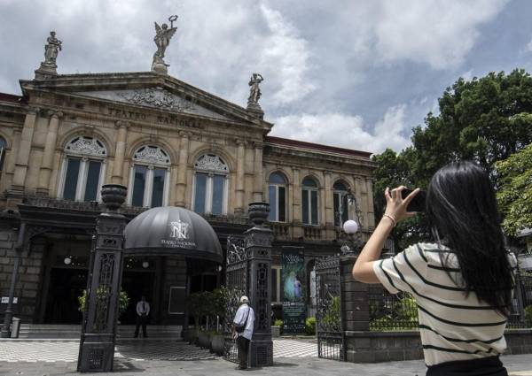 <i>Un turista toma una fotografía frente al Teatro Nacional de San José, el 18 de julio de 2024. El número de turistas que visitan Costa Rica aumentó un 14,5% en el primer semestre de este año, en comparación con el mismo período de 2023. FOTO Ezequiel BECERRA/AFP</i>