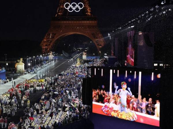 <i>Las delegaciones llegan al Trocadero mientras los espectadores observan al cantante francés Philippe Katerine actuando en una pantalla gigante durante la ceremonia de apertura de los Juegos Olímpicos de París 2024 en París el 26 de julio de 2024, mientras se ve la Torre Eiffel de fondo. FOTO Ludovic MARIN / POOL / AFP</i>