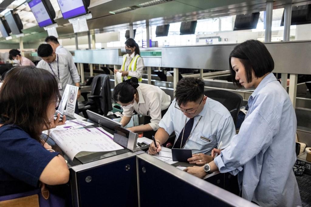 <i>El personal del aeropuerto registra manualmente a los pasajeros en el Aeropuerto Internacional de Hong Kong el 19 de julio de 2024, debido a una interrupción mundial de Microsoft. FOTO ISAAC LORENZO / AFP</i>